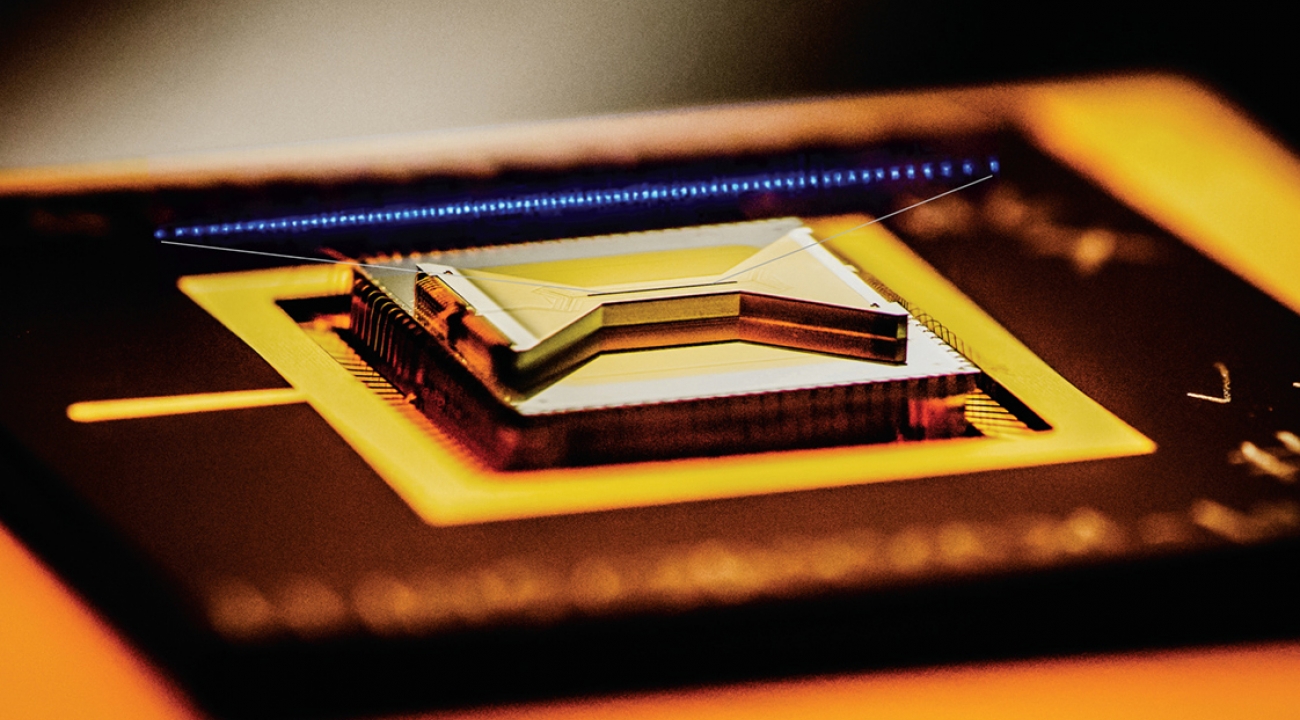 A semiconductor chip ion trap, fabricated by Sandia National Laboratories and used in research at the University of Maryland, composed of gold-plated electrodes that suspend individual atomic ion qubits above the surface of the bow-tie shaped chip. (Credit: Chris Monroe)